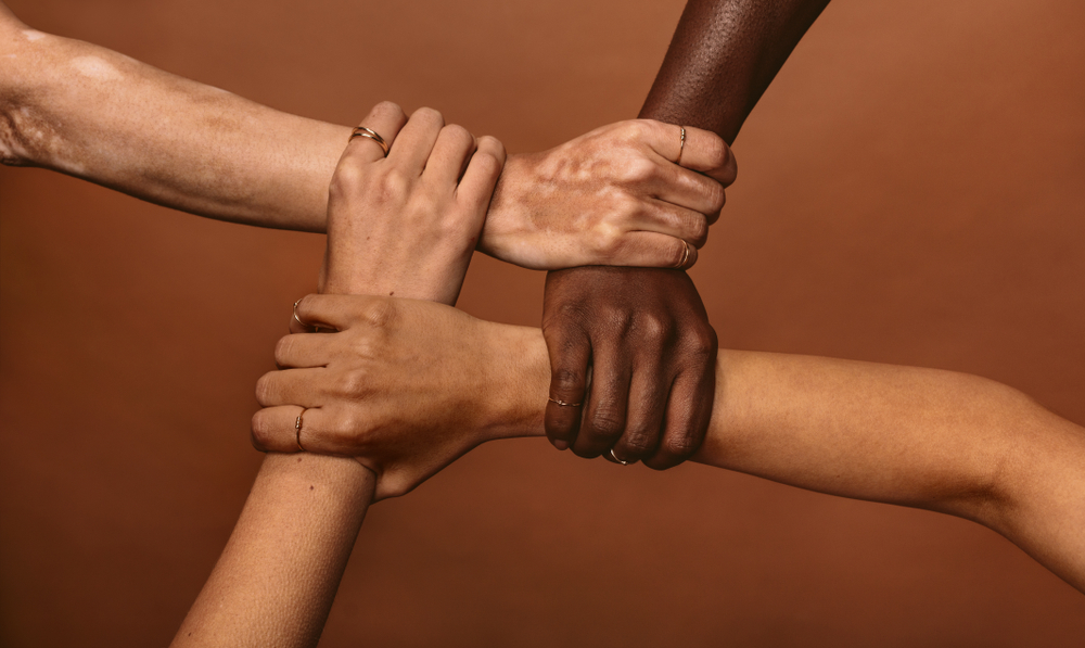 Hands of different ethnicities pictured together.
